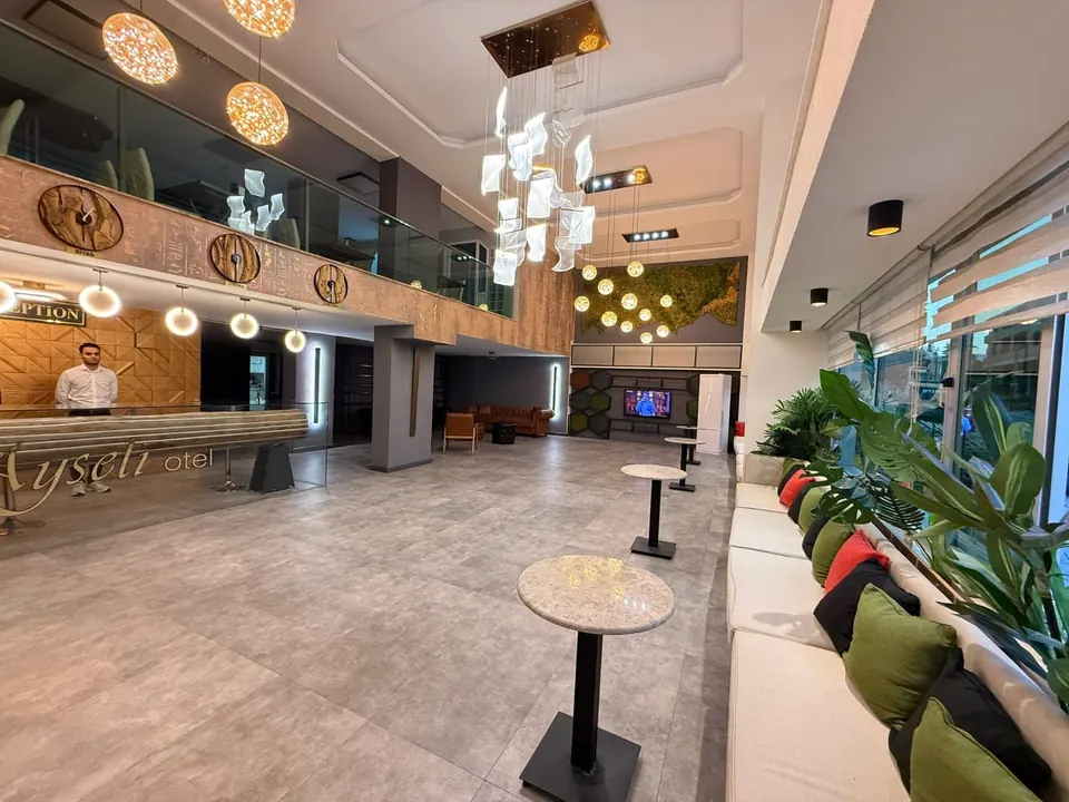 Ayseli Hotel'in yüksek tavanlı, bitkilerle çevrili ferah lobisi